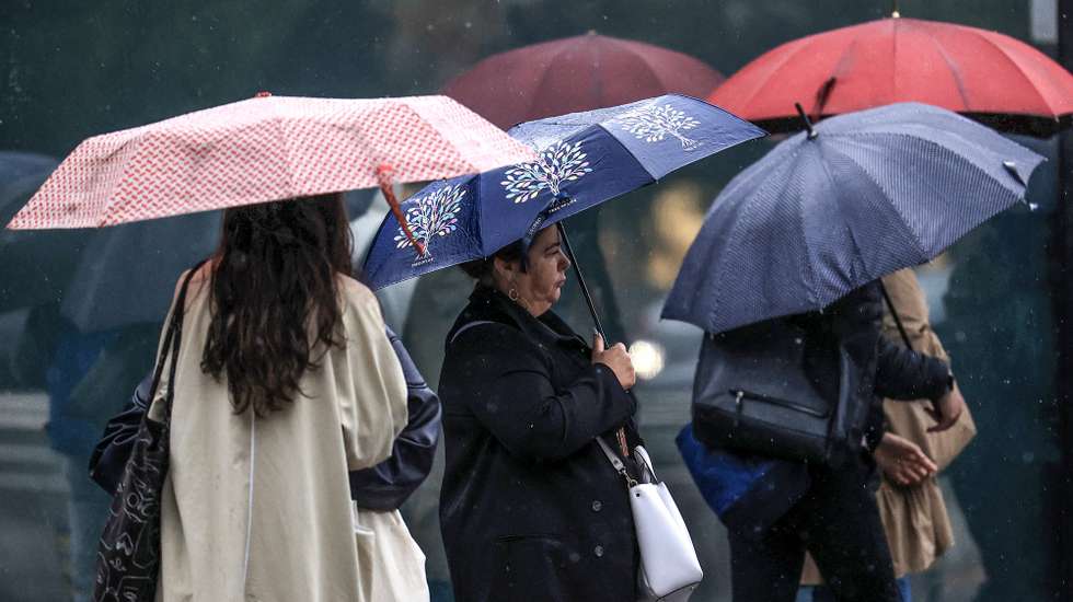 Jovens abrigam-se da chuva com um guarda-chuva junto ao Hospital São João, no Porto, 24 de setembro de 2024. De acordo com o Instituto Português do Mar e da Atmosfera (IPMA), prevê-se a ocorrência de períodos de chuva persistente a partir de hoje nas regiões Norte e Centro e que será por vezes forte na quarta e quinta-feira. ESTELA SILVA/LUSA