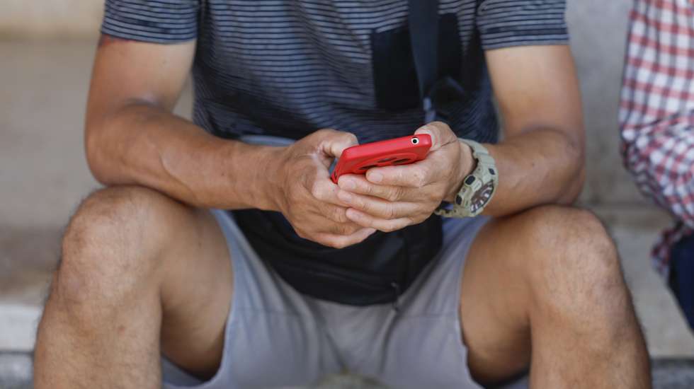 Um homem consulta o telemóvel na Praça de Londres, em Lisboa, 14 de agosto de 2025. Comunicações. Telefone. ANTÓNIO PEDRO SANTOS/LUSA