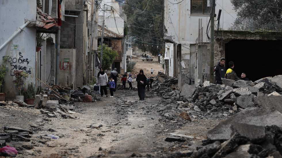 epa11103738 Palestinians walk along a damaged street at the Jenin refugee camp following an overnight Israeli raid in the West Bank city of Jenin, 25 January 2024. More than 25,700 Palestinians and at least 1,330 Israelis have been killed, according to the Palestinian Health Ministry and the Israel Defense Forces (IDF), since Hamas militants launched an attack against Israel from the Gaza Strip on 07 October 2023, and the Israeli operations in Gaza and the West Bank which followed it.  EPA/ALAA BADARNEH