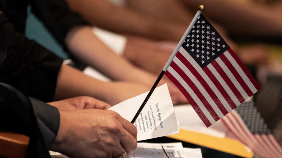 epa10873004 A new US citizen holds a small American flag over a paper with the lyrics of the national anthem during a US naturalization ceremony at the Los Angeles Central Library, in Los Angeles, California, USA, 20 September 2023. This ceremony takes place during Constitution Week. According to the latest numbers provided by the United States Citizenship and Immigration Services (USCIS), a total of 967,500 new citizens were welcomed in the fiscal year 2022.  EPA/ETIENNE LAURENT
