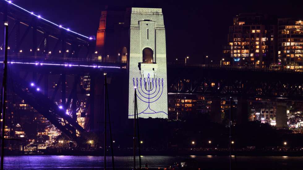 epa12619106 A menorah is projected onto the pylon of the Sydney Harbour Bridge during a tribute to the victim’s of the Bondi terror attack during the New Year's Eve Celebrations at Mrs Macquaries Point in Sydney, Australia, December 31, 2025.  EPA/DAN HIMBRECHTS NO ARCHIVING AUSTRALIA AND NEW ZEALAND OUT