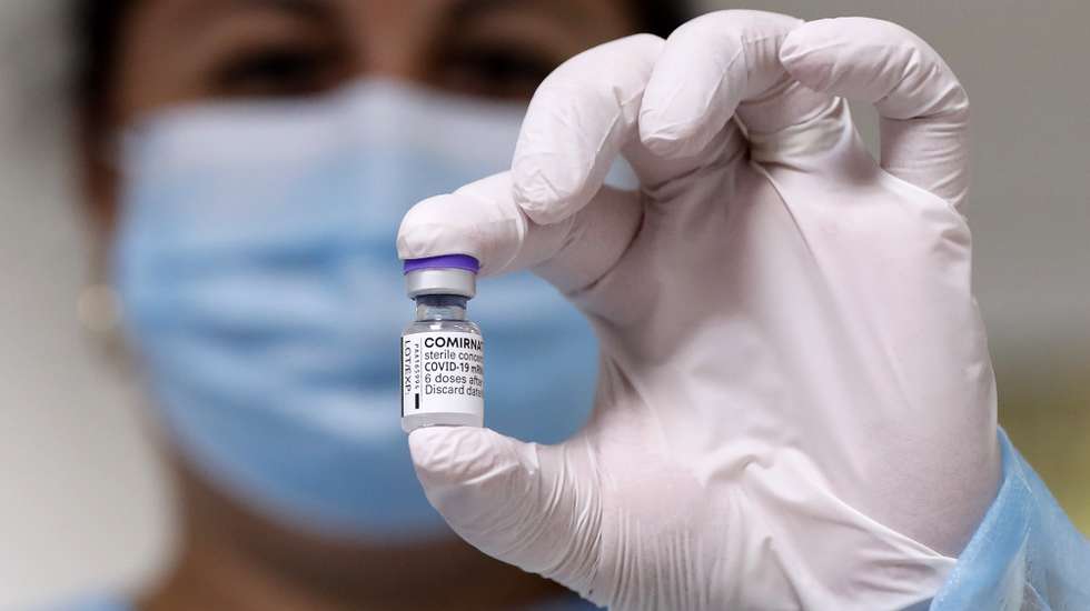 epa09492632 A Romanian nurse displays a vial of the vaccine against COVID-19 before a patient gets his booster injection, inside a jab boot organized at 'Matei Bals' Covid-19 hospital in Bucharest, Romania, 28 September 2021. Starting 28 September, Romanians with high health risk can be vaccinated with a third dose of the Pfizer-BioNTech Comirnaty vaccine against COVID-19.  EPA/ROBERT GHEMENT