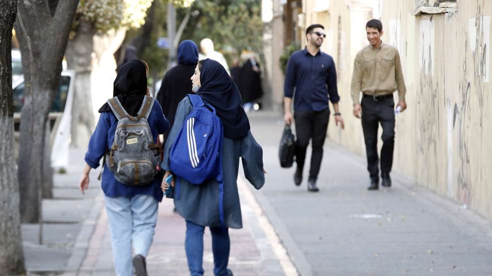 epa10234550 Iranian students walk past in a street in Tehran, Iran, 10 October 2022. Iran has been facing worldwide anti-government protests following the death of Masha Amini, a 22 year old girl, who was detained on 13 September by the police unit responsible for enforcing Iran's strict dress code for women. Amini was declared dead on 16 September, after she spent 3 days in a coma. Iranian leaders condemned the protests as 'riots' and accused US and Israel for planning the protests inside the country.  EPA/ABEDIN TAHERKENAREH