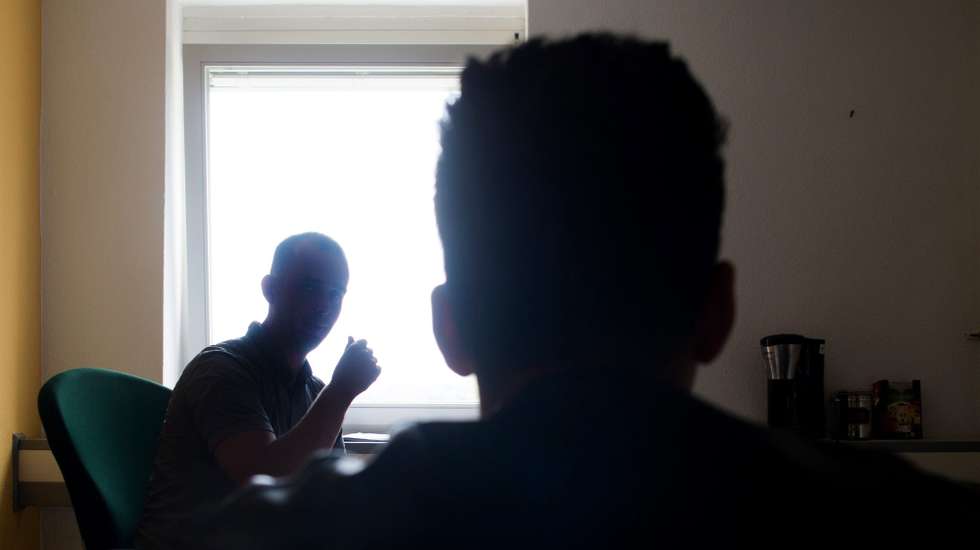 epa05443495 A Syrian migrant (R) sits in a hearing office of the federal department for migration and refugees (BAMF) at the Central Aliens Department of Brandenburg (ZABH) in Eisenhuettenstadt, Germany, 27 July 2016. The new arrival centre of the federal department for migration and refugees (BAMF) and the Brandenburgian ministry of the interior, which is located on the grounds, was officially opened today.  EPA/KLAUS-DIETMAR GABBERT