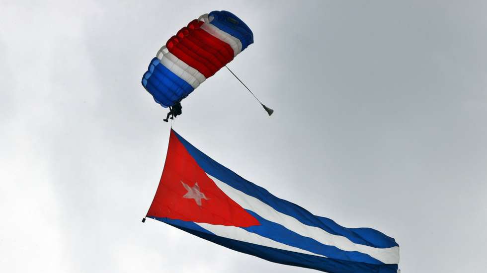 epa12296582 A parachutist holds a Cuban flag in Havana, Cuba, 12 August 2025. A team of parachutists kicked off a year-long program of events in Havana to commemorate Fidel Castro's centennial.  EPA/Ernesto Mastrascusa