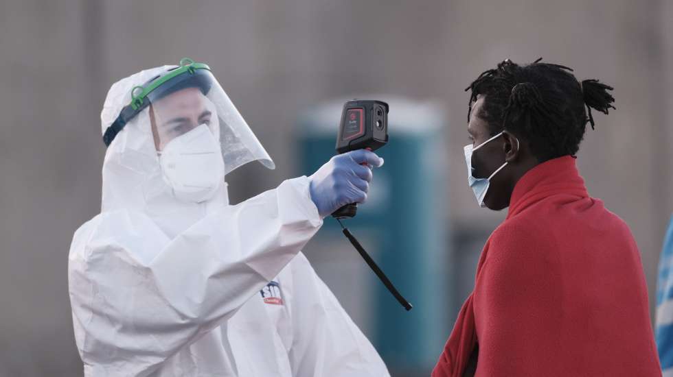 epa09086978 A Red Cross member checks the body temperature of a migrant rescued by Spanish Salvamento Maritimo upon arrival at Arguineguin's port in Gran Canaria, Canary Islands, Spain, 20 March 2021. Spanish Salvamento Maritimo rescued 52 SubSaharian migrants were rescued when they traveled on board a small boat.  EPA/ANGEL MEDINA G.