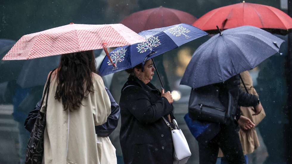 Jovens abrigam-se da chuva com um guarda-chuva junto ao Hospital São João, no Porto, 24 de setembro de 2024. De acordo com o Instituto Português do Mar e da Atmosfera (IPMA), prevê-se a ocorrência de períodos de chuva persistente a partir de hoje nas regiões Norte e Centro e que será por vezes forte na quarta e quinta-feira. ESTELA SILVA/LUSA