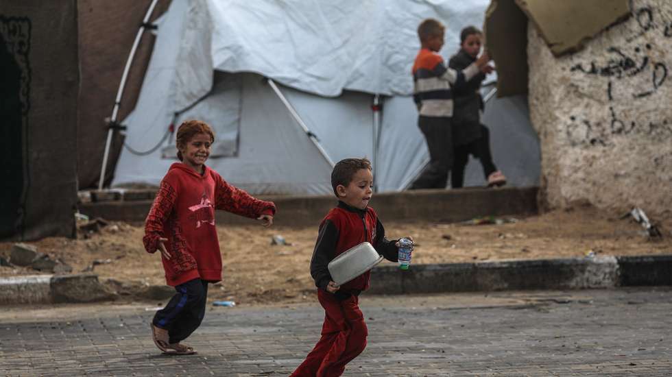 epa12525510 Displaced Palestinian children play outside their family's shelter during a rainy day at a makeshift camp, west of Gaza City, Gaza Strip, 14 November 2025. Around 1.9 million people in Gaza, nearly 90 percent of the population, have been displaced since the Israel-Hamas conflict began in October 2023, according to the UN.  EPA/MOHAMMED SABER