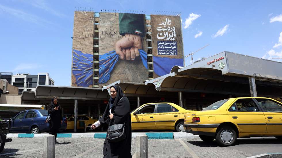 epa12935916 An Iranian woman walks near a huge billboard referring to the Strait of Hormuz and words reading in Persian 'Forever in Iran's hand' at Vanak square in Tehran, Iran, 06 May 2026. US President Donald Trump announced pausing the operation of escorting ships through the Strait of Hormuz, hinting at progress in peace talks with Tehran.  EPA/ABEDIN TAHERKENAREH