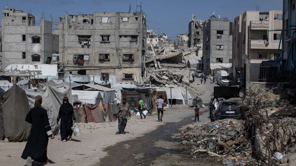 epa12432235 Internally displaced Palestinians walk past destroyed homes in Khan Younis, southern Gaza Strip, 5 October 2025. According to the UN around 90 percent of the population or 1.9 million people in Gaza have been displaced since the start of the conflict. More than 67,000 Palestinians have been killed in the Gaza Strip since October 2023, according to the Palestinian Ministry of Health, and about 1,200 Israelis have been killed since the launch of an Israeli military campaign in response to a cross-border attack by Hamas on 07 October 2023.  EPA/HAITHAM IMAD