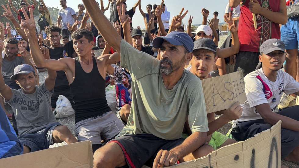 epa13176335 Migrants hold signs and raise their hands during a hunger strike at the El Trampolin beach campsite in Ceuta, Spain, 17 August 2026. The migrants entered the Spanish enclave from Morocco during the mass border crossings that began on 30 July.  EPA/LAURA RINCON