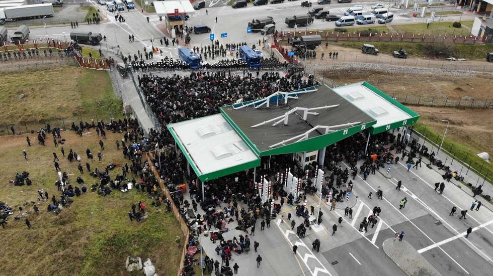 epa09584736 A handout photo made available by on 16 November 2021 by Belta news agency shows asylum-seekers, refugees and migrants gathering at the Bruzgi-Kuznica Bialostocka border crossing, Belarus, 15 November 2021. The asylum-seekers, refugees and migrants who arrived at the Polish border checkpoint Bruzgi-Kuznica Bialostocka broke through part of the barriers set up by Poland. Migrants from the Middle East began to leave the spontaneous camp near the border. It was noted that a large convoy of refugees, accompanied by Belarusian security officials, went out towards the frontier checkpoint Bruzgi. Since November 08, several thousand migrants have been trying to enter the EU and have set up camp in a forest belt adjacent to the border. Polish authorities refuse to admit refugees.  EPA/LEONID SCHEGLOV / BELTA HANDOUT HANDOUT MANDATORY CREDIT HANDOUT EDITORIAL USE ONLY/NO SALES