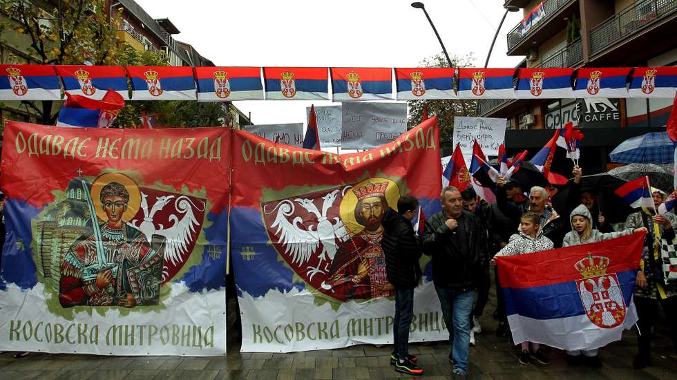epa10290173 People walk past banners reading 'No turning back from here, Kosovska Mitrovica' during a rally in Northern Mitrovica, Kosovo, 06 November 2022. Kosovo Serbs protested after a dispute over license plates and personal documents that triggered a Serb walkout from their jobs in institutions of Republic of Kosovo.  EPA/DJORDJE SAVIC