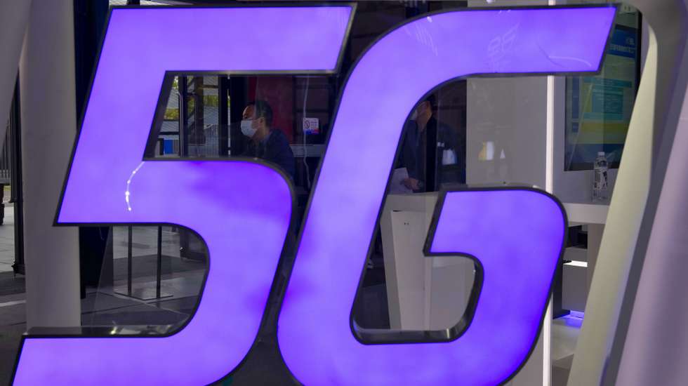 epa08837103 A man is seen behind 5G logo on the Foxconn booth on “Light Of The Internet Expo” during World Internet Conference in Wuzhen, Zhejiang Province, China, 23 November 2020. The World Internet Conference, also known as Wuzhen Summit is a two day conference held on 23 to 24 November.  EPA/ALEX PLAVEVSKI