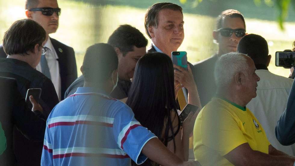 epa09152813 President of Brazil Jair Bolsonaro (C) speaks with supporters outside the Palacio da Alvorada, in Brasilia, Brazil, 22 April 2021. Around 40 international leaders attended the summit called by US President Biden. The meeting is intended to underline the urgency and economic benefits of stronger climate action on the road to the United Nations Climate Change Conference (COP26) in Glasgow in November 2021.  EPA/JOEDSON ALVES