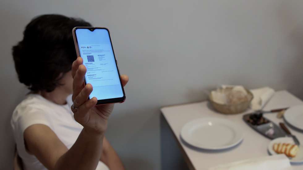 Cliente exibe o certificado digital no interior de um restaurante em Lisboa, após o Governo decreta que os restaurantes em concelhos de risco elevado ou muito elevado – um total de 60 – passam a ter de exigir certificado digital ou teste negativo à covid-19 a partir das 19:00 de sexta-feira e aos fins de semana para refeições no interior, Lisboa, 10 de julho de 2021. As pessoas em esplanadas que precisarem de entrar nos restaurantes para acesso aos serviços comuns, como instalações sanitárias, ou para efetuarem pagamento, estão dispensadas de apresentar um teste negativo à covid-19 ou o certificado digital. MANUEL DE ALMEIDA/LUSA