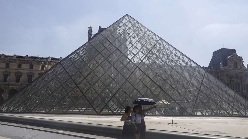 epa12206658 Tourists walk with umbrellas to protect themselves from the sun around the Louvre museum during a hot day in Paris, France, 30 June 2025. From 01 July, Paris and the entire Ile-de-France region, as well as 16 other departments, will be under red alert for extreme heatwave conditions, with temperatures expected to reach 36 to 40 degrees Celsius, with peaks of 41 degrees. This red alert level was last triggered in the Ile-de-France region in August 2020.  EPA/TERESA SUAREZ