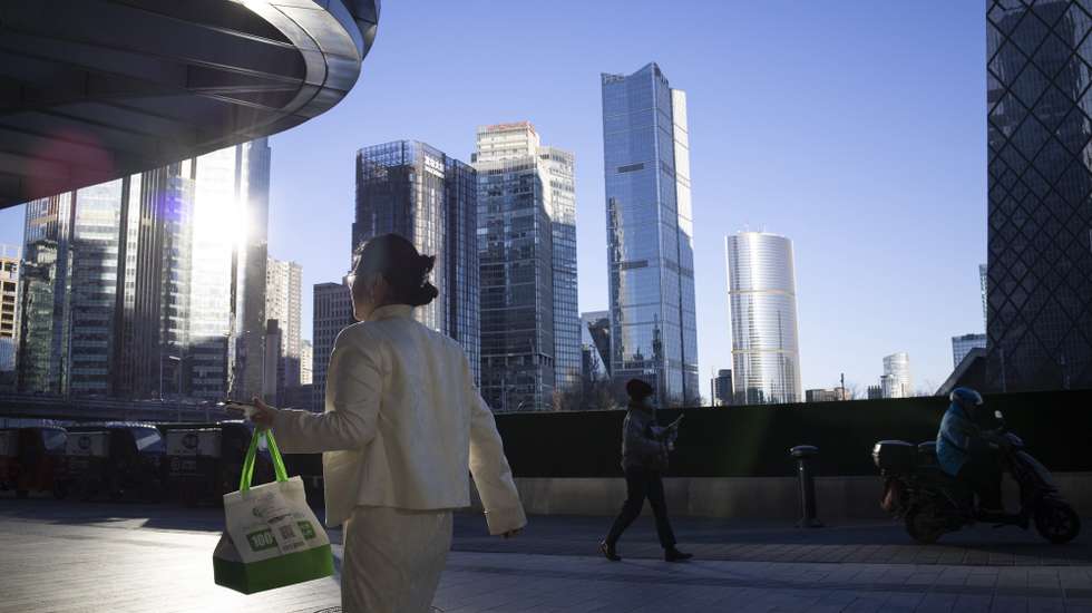 epaselect epa12618741 A woman carries a delivery bag as she walks along a sidewalk in the Central Business District of Beijing, China, 31 December, 2025. The Composite Purchasing Managers Index Output Index of the National Bureau of Statistics went from 49.7 in November to 50.7 in December 2025.  EPA/ANDRES MARTINEZ CASARES