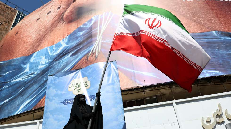 epa12946980 A veiled woman holds Iran’s national flag in front of a huge anti-US billboard referring to US President Donald Trump and the Strait of Hormuz at Valiasr Square in Tehran, Iran, 11 May 2026. US President Donald Trump says Iran’s counter-proposal to end the ongoing conflict is not acceptable.  EPA/ABEDIN TAHERKENAREH