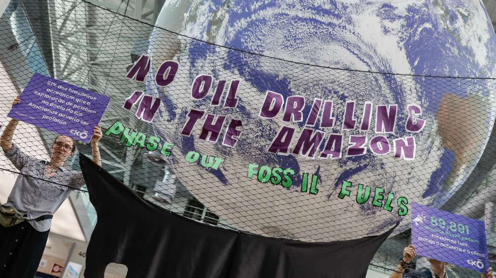 epa12535964 A group of people from the Eko community hold signs with messages calling for a halt to Brazilian oil company Petrobras' plans to explore near the mouth of the Amazon River during COP30 in Belem, Brazil, 19 November 2025.  EPA/FRAGA ALVES