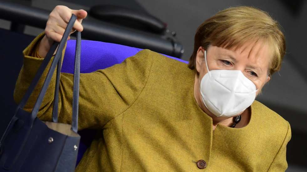 epa08970475 German Chancellor Angela Merkel lifts her handbag after a government declaration on the annual economic report 2021 in the German parliament Bundestag in Berlin, Germany, 28 January 2021.  EPA/CLEMENS BILAN