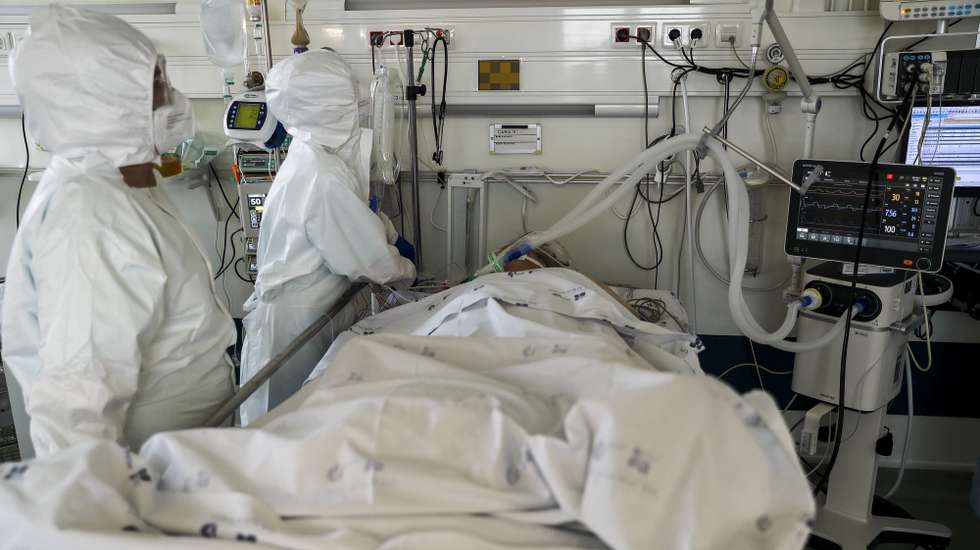 Dois elementos da equipa médica cuidam de uma paciente hospitalizado na Unidade de Cuidados Intensivos covid-19