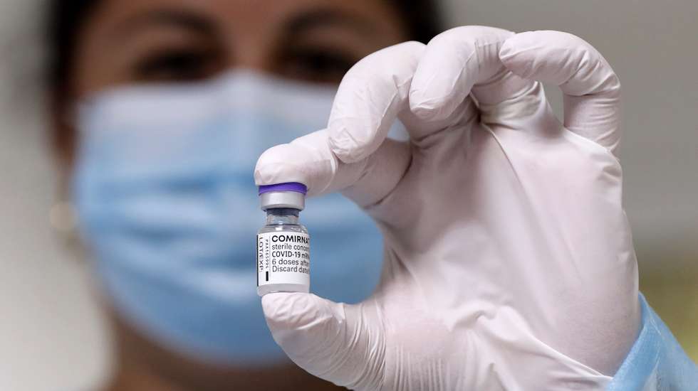 epa09492632 A Romanian nurse displays a vial of the vaccine against COVID-19 before a patient gets his booster injection, inside a jab boot organized at 'Matei Bals' Covid-19 hospital in Bucharest, Romania, 28 September 2021. Starting 28 September, Romanians with high health risk can be vaccinated with a third dose of the Pfizer-BioNTech Comirnaty vaccine against COVID-19.  EPA/ROBERT GHEMENT