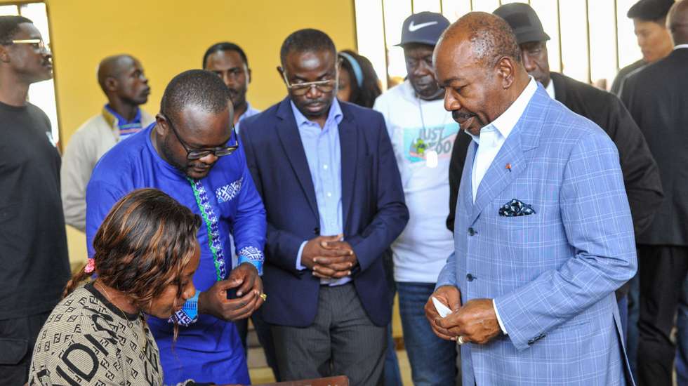 epa10821767 Gabonese President Ali Bongo Ondimba (R), speaks with an election official after casting his vote during the 2023 Gabonese general elections in Libreville, Gabon, 26 August 2023. A little under 850,000 registered voters out of a population of of 2.3 million are to decide whether to give President Ali Bongo Ondimba a third term.  EPA/STR