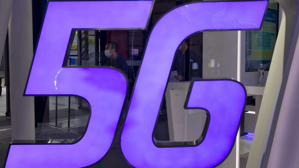 epa08837103 A man is seen behind 5G logo on the Foxconn booth on “Light Of The Internet Expo” during World Internet Conference in Wuzhen, Zhejiang Province, China, 23 November 2020. The World Internet Conference, also known as Wuzhen Summit is a two day conference held on 23 to 24 November.  EPA/ALEX PLAVEVSKI