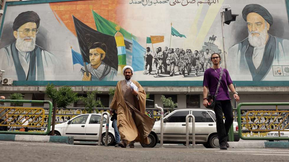 epa12055729 An Iranian cleric walks near a huge wall painting of Iranian supreme leader Ayatollah Ali Khamenei (Top-L), and late supreme leader Ayatollah Ruhollah Khomeini (Top-R) in a street in Tehran, Iran, 26 April 2025. Iran and the US will hold a third round of nuclear talks on 26 April in the Omani capital of Muscat.  EPA/ABEDIN TAHERKENAREH