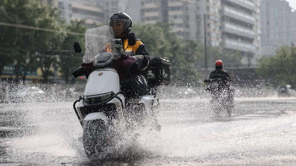 epa13162651 A person rides a scooter in the rain in Beijing, China, 12 August 2026. Beijing activated a Level II flood-control emergency response on 11 August. According to the Beijing Meteorological Observatory, heavy rain is expected from 11 to 13 August.  EPA/WU HAO