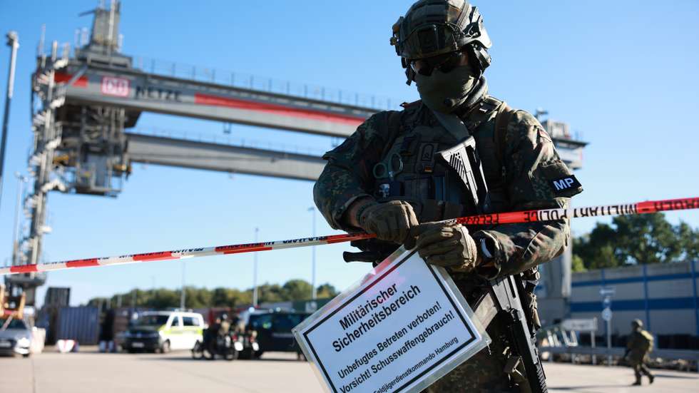 epa13262846 A Military Police officer with a rifle installs a warning sign for a military security area during a staged drone attack incident at a freight yard of German railways Deutsche Bahn during the military exercise 'Red Storm Charlie' in Hamburg, Germany, 25 September 2026. Around 500 officers from the German Armed Forces (Bundeswehr) and civilian emergency services took part in a joint defence exercise aimed at practising civil defence protocols and crisis response.  EPA/CLEMENS BILAN