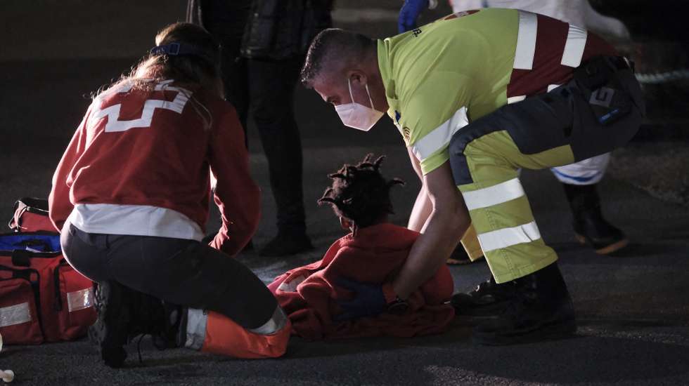 epa09078930 Two Red Cross volunteers help a baby on arrival at Arguineguin port in Gran Canaria, Canary Islands, Spain 16 March 2021. Spanish Sea Rescue intercepted a small boat with 52 sub-Saharan migrants five miles from Gran Canaria island.  EPA/Angel Medina G.