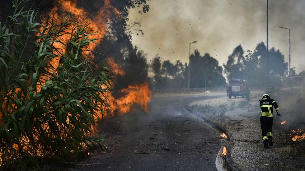 Um bombeiro protege-se do fogo durante o incêndio florestal em Andrinos, às portas da cidade de Leiria, 13 de julho de 2022. Dezasseis dos 18 distritos de Portugal continental estão hoje sob aviso vermelho, o mais grave, devido ao tempo quente, com mais de uma centena de concelhos em perigo máximo de incêndio rural. NUNO ANDRÉ FERREIRA/LUSA