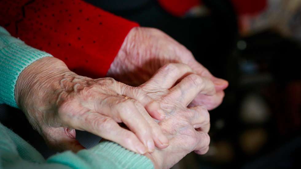 epa08786229 Two friends resident hold each other hands while they watch TV show at the 'Notre Dame De Bonne Esperance' nursing home in Chatelet, Belgium, 30 October 2020. Due to COVID-19, residents of the nursing home are not allowed to leave among the measures taken to protect residents from the spread of coronavirus.  EPA/STEPHANIE LECOCQ