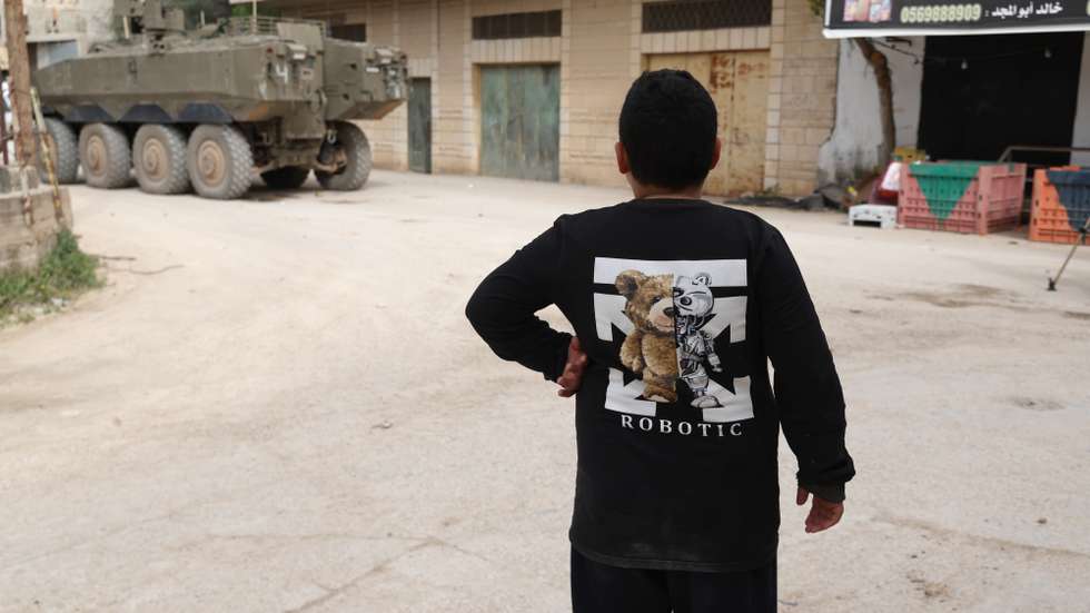 epa12750911 A Palestinian boy stands at a street as Israeli troops conduct a military raid in the village of Al-Yamoun, west of Jenin, West Bank, 17 February 2026.  EPA/ALAA BADARNEH