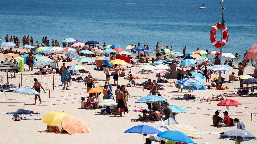 Mesmo com a bandeira vermelha hasteada correspondente à ocupação plena da praia devido à pandemia provocada pela covid-19, as pessoas aproveitam as altas temperaturas que se fazem sentir, na praia de Carcavelos, Cascais, 05 de julho de 2020. ANTÓNIO COTRIM/LUSA