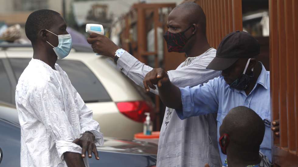 epa08973731 A mosque official takes the body temprature of a worshipper with a thermometer at the entrance to the Lagos central mosque during a Jumaat service in Lagos, Nigeria, 29 January 2021. Despite the public doubts to the reality of coronavirus pandemic in Nigeria, many religious worship places such as the Lagos central mosques, are asking their members to comply with Covid-19 preventive protocols.  EPA/AKINTUNDE AKINLEYE
