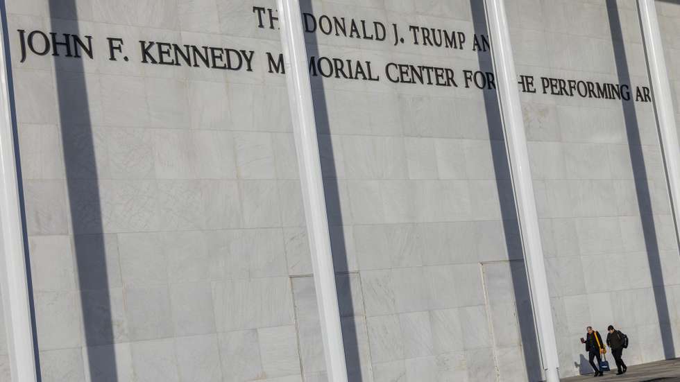 epa12605254 People walk by new signage showing US President Donald J. Trump's name above former President John F. Kennedy's on the John F. Kennedy Memorial Center for the Performing Arts building, in Washington, DC, USA, 20 December 2025. Kennedy Center's board of trustees, hand-picked by President Trump, voted to rename the institution 'The Donald J. Trump and The John F. Kennedy Memorial Center for the Performing Arts.' While the center has already updated its branding and building signage, a formal name change would likely require an Act of Congress.  EPA/SHAWN THEW