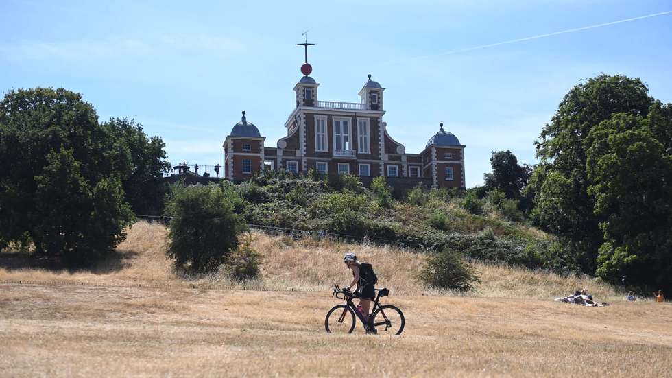epa10108877 A woman pushes a bike on parched ground in Greenwich Park in London, Britain, 06 August 2022. Southern England has experienced the driest July since records began. With another heatwave expected in the coming weeks, there are fresh concerns regarding a prolonged drought, with fears of water shortages.  EPA/NEIL HALL