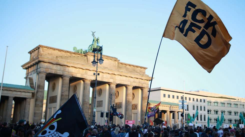 epa13220463 A participant waves a flag that reads 'FCK AFD' during a rally at the Brandenburg Gate in Berlin, Germany, 07 September 2026. The protest was scheduled a day after the far-right Alternative for Germany party (AfD) won the election in the regional state of Saxony Anhalt by a wide margin.  EPA/CLEMENS BILAN