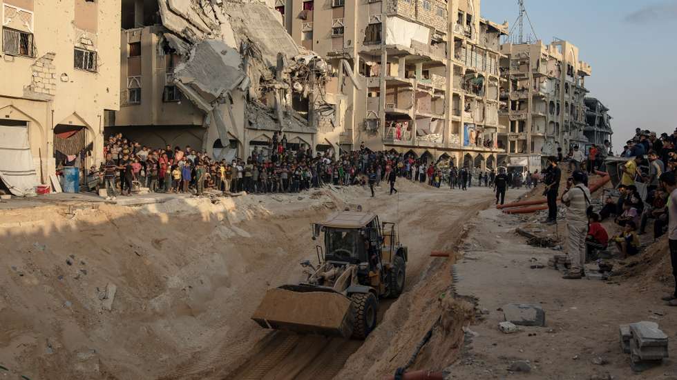 epaselect epa12460750 Locals gather to watch as an excavator works at the site where members of the Al-Qassam Brigades, the military wing of the Hamas movement, are searching for the bodies of Israeli hostages in an area in Hamad City, Khan Younis, in the southern Gaza Strip, 17 October 2025.  EPA/HAITHAM IMAD