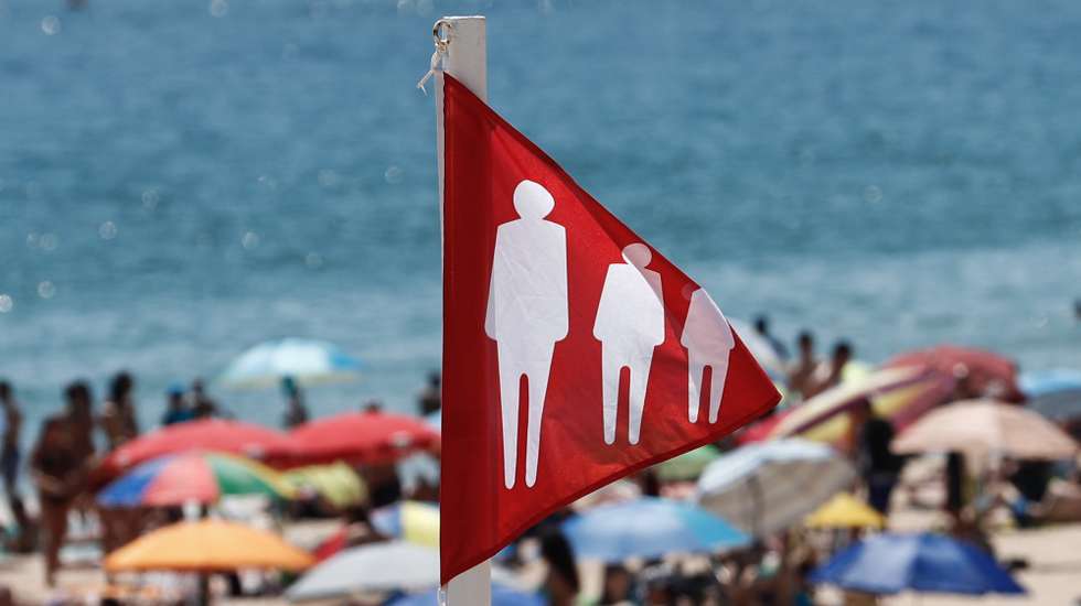 Mesmo com a bandeira vermelha hasteada correspondente à ocupação plena da praia devido à pandemia provocada pela covid-19, as pessoas aproveitam as altas temperaturas que se fazem sentir, na praia de Carcavelos, Cascais, 05 de julho de 2020. ANTÓNIO COTRIM/LUSA