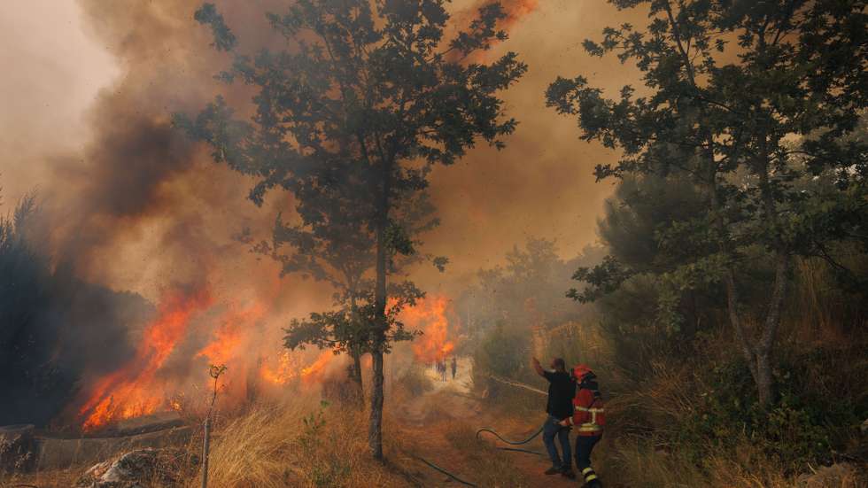 Um bombeiro e um popular durante o combate a um incêndio na Aldeia de Gontães, Vila Real, 4 de agosto de 2025. Pelas 16:30, mais de 2.200 operacionais e cerca de 710 meios de transporte, inclusive 19 meios aéreos, combatiam 63 incêndios rurais em Portugal continental, com destaque para os fogos em Vila Real e Celorico de Basto (distrito de Braga), segundo a Proteção Civil. PEDRO SARMENTO COSTA/LUSA
