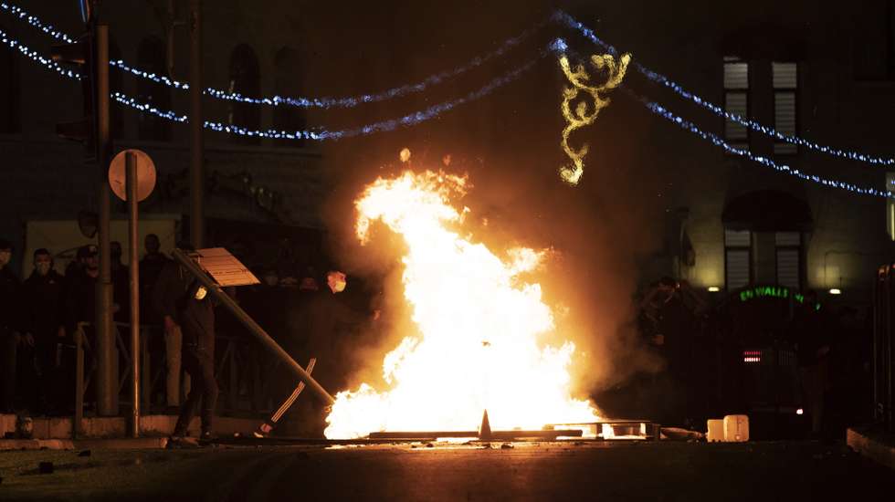 epa09153861 Palestinian protesters stand next to a burning barricade during clashes between Palestinian and Israeli police next to the Damascus gate of Jerusalem's old city, 22 April 2021. Israeli Police and Palestinians clashed as Israeli Police increases restriction in the area after reports of a march by Lehava, a jewish far-right extremist group.  EPA/ATEF SAFADI