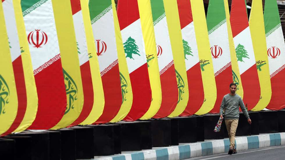 epaselect epa11672953 An Iranian man walks past a decoration of Iranian-Lebanese and Hezbollah flags in a street in Tehran, Iran, 21 October 2024. Iranian supreme leader Ayatollah Ali Khamenei on 19 October issued a message over the death of Yahya Sinwar, stating that 'the resistance did not stop after the death of its leaders, and it will not stop'. The Israeli Army, Tsahal, on 17 October 2024 confirmed that Hamas leader Yahya Sinwar was 'eliminated' on 16 October 'after a year-long pursuit'.  EPA/ABEDIN TAHERKENAREH