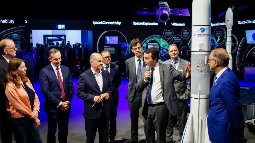 epa11390780 German Chancellor Olaf Scholz (4-L), stands next to German Minister for Transport and Digital Affairs Volker Wissing (3-L) as CEO of ArianeGroup Martin Sion (7-L) talks on front of an Ariane 6 model during the opening round tour of the ILA Berlin Air Show 2024 in Selchow, Germany, 05 June 2024. The aerospace and defense industry exhibition takes place at the inactive Berlin-Brandenburg airport from 05 June to 09 June 2024.  EPA/CLEMENS BILAN