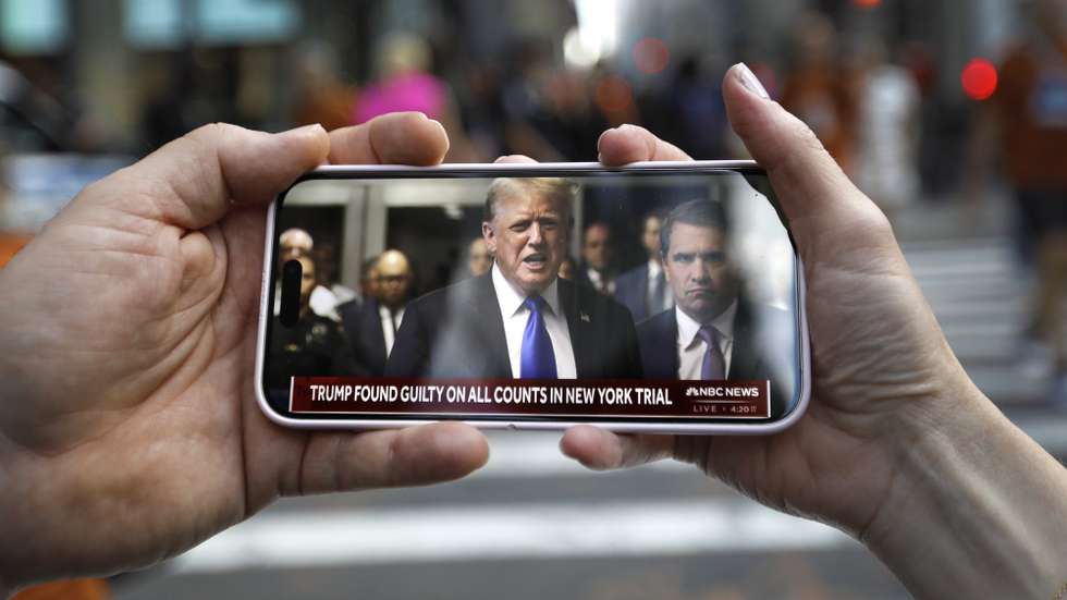 epa11380833 Two people watch Former US President Donald Trump at criminal court speak on their mobile phone outside Trump Tower after a jury found former US President Donald Trump guilty on all 34 counts in his criminal trial in New York State Supreme Court in New York, New York, USA, 30 May 2024. Trump was found guilty on all 34 felony counts of falsifying business records related to payments made to adult film star Stormy Daniels during his 2016 presidential campaign.  EPA/PETER FOLEY