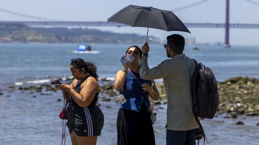 epa13080321 People shelter from the sun under an umbrella near the Tagus River at Cais das Colunas during a heatwave in Lisbon, Portugal, 02 July 2026. The national weather agency (IPMA) has issued high-level red alerts due to a spell of extreme heat that is expected to last for at least a week.  EPA/JOSE SENA GOULAO