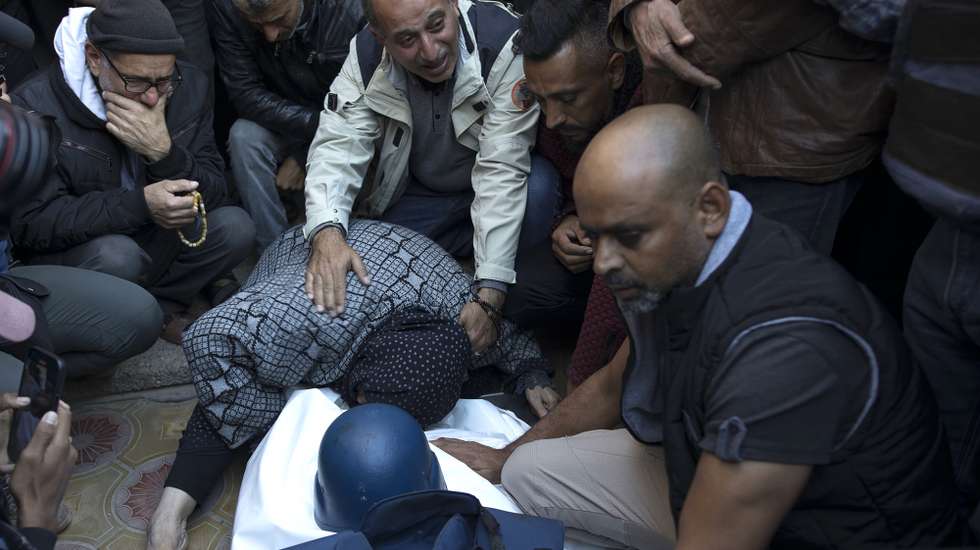 epa11032003 Relatives of Palestinian journalist Samer Abu Daqqa, cameraman for Al Jazeera, who was killed during Israeli air strikes in the southern Gaza Strip, with press crews next to his wrapped body, outside Nasser Hospital in Khan Yunis, southern Gaza Strip, 16 December 2023. More than 18,000 Palestinians and at least 1,200 Israelis have been killed, according to the Palestinian Health Ministry and the Israel Defense Forces (IDF), since Hamas militants launched an attack against Israel from the Gaza Strip on 07 October, and the Israeli operations in Gaza and the West Bank which followed it.  EPA/HAITHAM IMAD